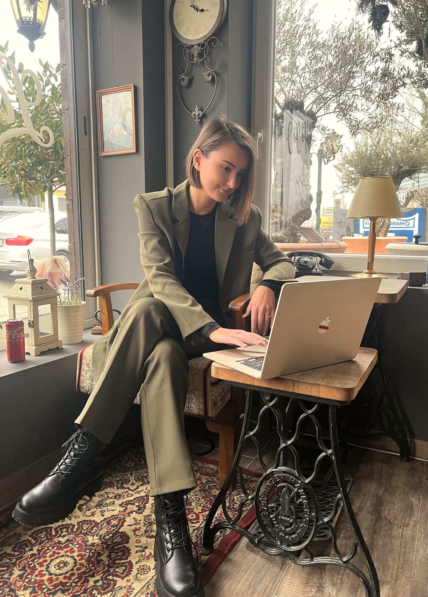 Adrijana sjedi prekriženih nogu u fotelji i tipka po laptopu na starinskom stoliću.